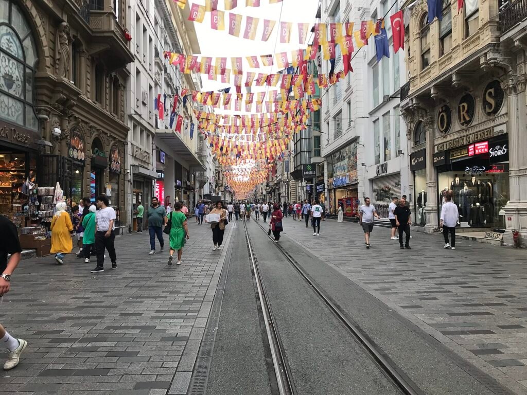Drukke winkelstraat met voetgangers en een historische rode tram in Istanbul
