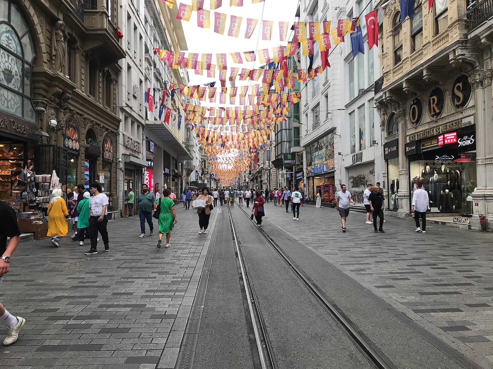 Drukke winkelstraat met voetgangers en een historische rode tram in Istanbul