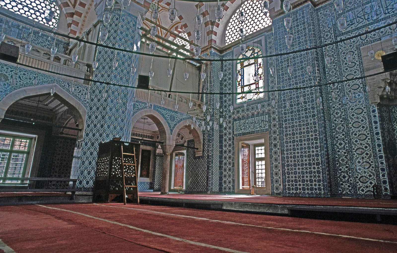 Muren vol blauwgroene Iznik-tegels met bloemmotieven in een moskee-interieur