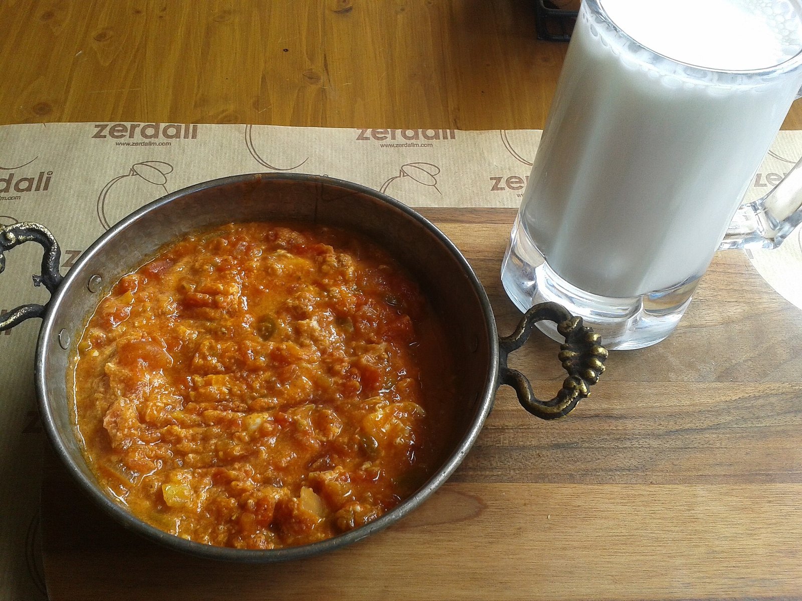 Pan met roerei, tomaat en groene peper naast een glas thee